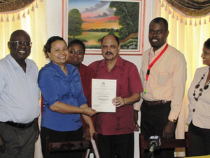Minister of Health Dr. Bheri Ramsaran hands over the provisional licence to Feena Lagan of the Cancer Institute, at the Ministry of Health on Tuesday. alt