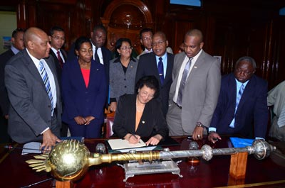 Geerlings-Simons signs the Parliament guest book as members of her delegation and Trotman look on.