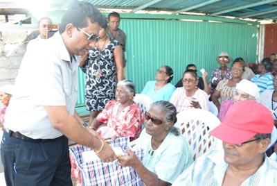 Minister of Legal Affairs and Attorney General, Anil Nandlall presents a hamper to a senior citizen at a Christmas party at Annandale yesterday