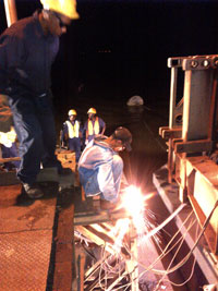 A welder severs the damage transom from the connecting plates on Wednesday night