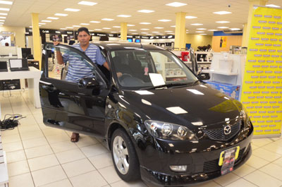 ‘TIMELY ACQUISITION’: Electrician, François Koo, is all smiles as he stands by the new car he won from Courts Guyana Inc (Adrian Narine photos)