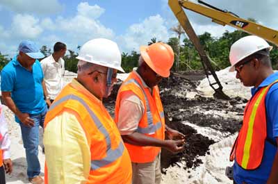 President Donald Ramotar looks on as Minister of Public Works, Robeson Benn does a quick test of the soil at the airport