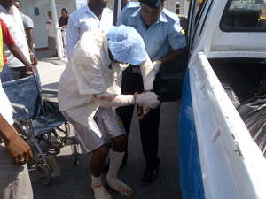 A police rank assists Linus La Cruz into a waiting police vehicle after landing at the Ogle Airport yesterday (Photo by Leroy Smith)