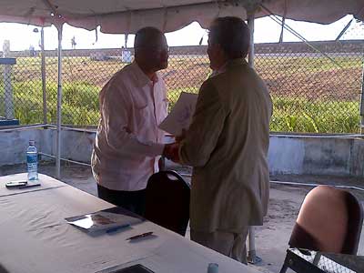 Minister Clement Rohee and Ambassador Hardt shake hands after signing the document to signal the official handing over of the machine