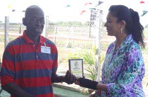 Longest-serving employee Ovid Hawke receives his award from Mrs Ahilia Panday,