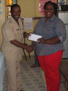 Commander Hicken hands over a monetary donation to the tutor of the programme to assist with the initial startup.
