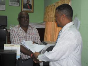  CCWU General President, Sherwood Clarke presents a copy of the agreement to Chief Labour Officer, Mr. Charles Ogle