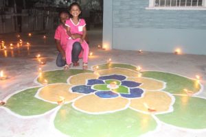 These two young ladies assist their parents in decorating their yard with diyas 
