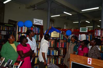 Chairman of the Committee of the National Library, Pitamber Persaud, and a student unveiling the Plaque