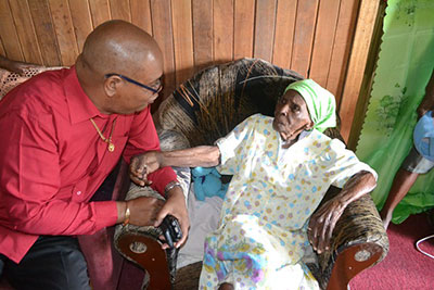 Mr. Edghill interacting with Agatha Campbell of Christianburg during the distribution of hampers in Region Ten