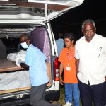 Transport Minister Robeson Benn, observing the loading of bodies into the hearse, ensures they are properly covered