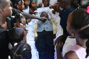 Children of the neighbourhood and others pay their last respects to a fallen friend and brother
