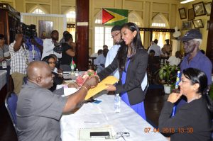 TUF Leader Marissa Nadir handing over her documents to GECOM’s Chief Elections Officer Keith Lowenfield 