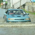 A driver ‘boating’ his way through the flood waters on Lama Avenue, Bel Air Park, just outside the Guyana Chronicle yesterday morning