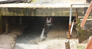 A worker from a private company uses a hose to clear the outfall of the Church Street sluice 