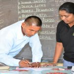 Colin Adrian signs the legal document as he affirms his position as Toshao, in the presence of the returning officer and the Regional Information Officer for Region 5, Sandie Ross-Hendricks 