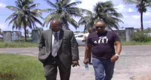 Shawn Hinds, right, accompanied by Nigel Hughes, enters the CID compound, Eve Leary