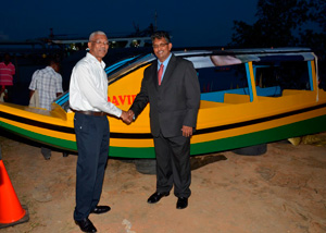 President David Granger being presented with a boat to be used for ferrying children in riverine communities to school, by Chief Executive Officer of GAICO Construction and General Services Incorporated Komal Singh