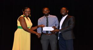 Guyana’s 50th Anniversary celebration logo design winners Chris Taylor and Compton Babb collecting their winning cheque from Minister within the Ministry of Education, Department of Culture, Youth and Sport Dr. Nicolette Henry