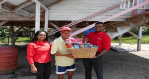 Joseph Barker as he accepts a basket of goodies from Digicel representatives Vidya Sanichara and Jason Lampley