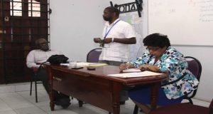 Mr Charles Corbin (standing) makes a point, in the presence of Ministers Winston Felix and Amna Ally 