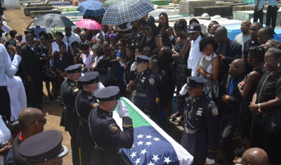 The casket, draped with the flag of the NYPD and containing the body of Randolph Holder, is rested on the ground at the Le Repentir Cemetery, before being placed in the tomb [Cullen Bess-Nelson photo)