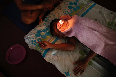 An inmate tends to a fellow prisoner while performing ear candling.