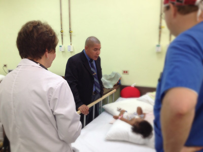 Minister Norton speaks with one of the children as two members of the medical team look on