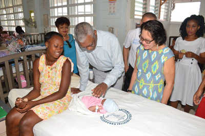 President Granger meeting Christmas baby Tatianna, as First Lady Sandra Granger, Minister Amna Ally, Staff Nurse Michelle Holder and the baby's mother, Venetia, look on