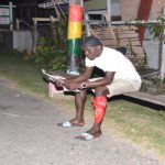 A young man reads about Baby Arthur in the Guyana Chronicle under a lamp post last evening (Delano Williams photo)