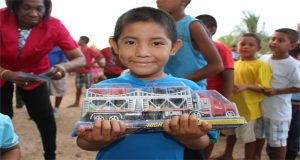 A little boy beams as he displays his new toy truck. 