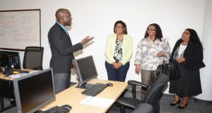 Minister of Telecommunications, Cathy Hughes, and Minister of Social Protection, Volda Lawrence, listen keenly as a staff explains the operations of the company. At right is Dr Dale Dan, Vice President of Operations in Guyana 