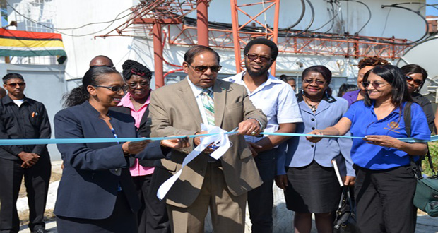 Prime Minister Moses Nagamootoo, assisted by NCN’s Chief Executive Officer Molly Hassan, cuts the ceremonial ribbon to commission the Satellite Earth Station Multimedia Teleport at the National Communications Network [NCN) (GINA photo)