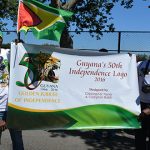 Artists Compton Babb and Christopher Taylor, who designed the 50th Independence Anniversary Logo, hold a banner outside of the South Shore High School, Brooklyn, New York on Sunday following the Guyana Mashramani Parade