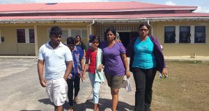 Pam Chandradeo, second right, comforts her nine-year-old daughter as they leave the Mibircuri hospital with other relatives. The woman’s husband Pawan, her sixteen-year-old son Kevin, and her brother Naresh Rooplall were shot dead. Rooplall’s widow, Shoba Luckicharran, is at second left. 