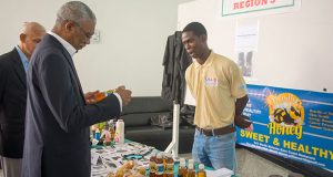 President David Granger shares a moment with young entrepreneur Akeem Williams, who sells his pure honey product under the “Friendly Bee” brand. 
