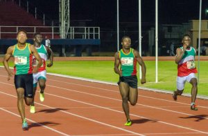 Guyana’s Compton Ceasar (left) making his way to the finish line in the boys’ 100m