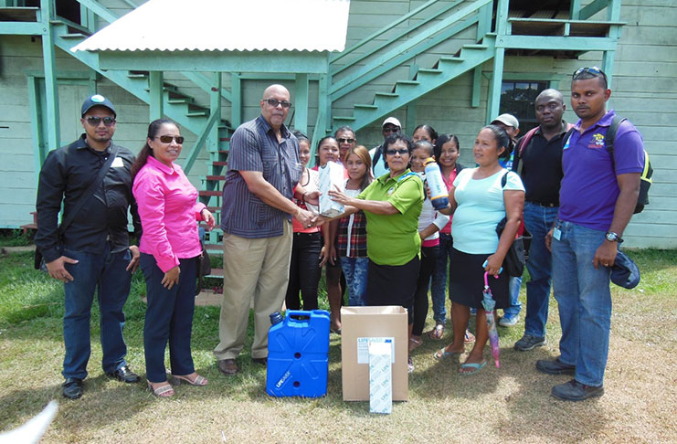 GWI’s Managing Director Dr. Richard Van West-Charles hands over filters to Toshao of Kamarang/Warawatta Ms. Norma Thomas, as Minister within the Ministry of Communities Dawn Hastings (second left), GWI officials and residents look on.