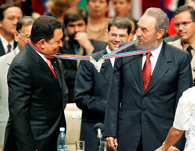 Venezuela’s President Hugo Chavez (L) and his Cuban counterpart Fidel Castro joke after joining their medallions, given by medical graduates, at Havana’s Karl Marx theatre, in this August 20, 2005 file photo. (REUTERS/Claudia Daut/File Photo)