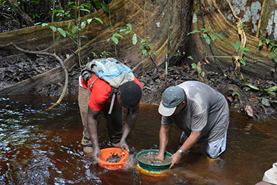 Three casual workers sift out the sediments with a colander and a batel. 