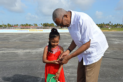 President David Granger gives this little girl a 50th Anniversary commemoration coin just before his departure from Region Two 