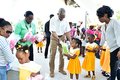 This little lady receives a stuffed toy from President David Granger as Ministers Simona Broomes and Annette Ferguson assist with the distribution at Buxton