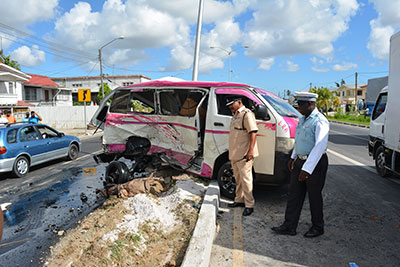 ‘A’ Division Traffic Officer-in-Charge, Superintendent Ramesh Ashram, and another rank inspect the oil spilled onto the carriageway at the accident scene, as sand is spread to minimize the hazard to other drivers 
