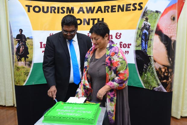 Minister Irfaan Ali cutting the cake with THAG executive member Ms Andrea De Caires at the launch of Tourism Awareness Month.