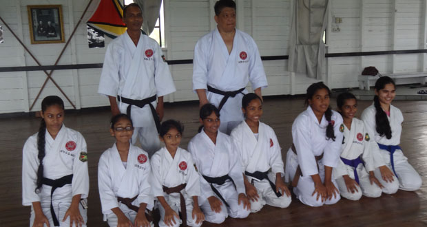 Master Frank Woon-a-Tai and Sensei Jeffrey Wong, strike a pose with female karatekas of the Guyana Karate College after the grading sessions.