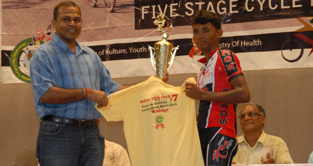 Minister of Sport, Dr. Frank Anthony (left), presents the overall winner of the seventh annual National Sports Commission/Ministry of Sport/Ministry of Health/Guyana Cycling Federation ‘Ride for Life’ five-stage road race, Raynauth Jeffrey, with his championship trophy and jersey, while Director of Sport, Neil Kumar (center), looks on appreciatively. (Photo by Sonell Nelson)