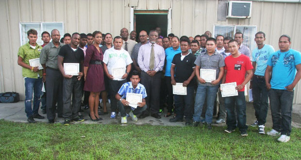 Prime Minister Samuel Hinds along with Guyana Power and Light officials and the graduates pose for a group picture showing off their qualifications