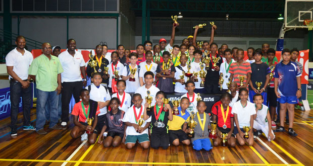 An elated group of young table tennis winners pose with their spoils after the completion of the Digicel Inter-School table tennis championships at the Cliff Anderson Sports Hall last night. Looking on approvingly from left are national coach Linden Johnson, GTTA president Godfrey Munroe and Digicel’s Gavin Hope. (Adrian Narine photo)