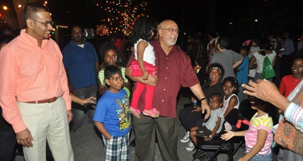 Donald Ramotar and Minister of Natural Resources and the Environment engage some of the children present at the tree light up in the National Park.
