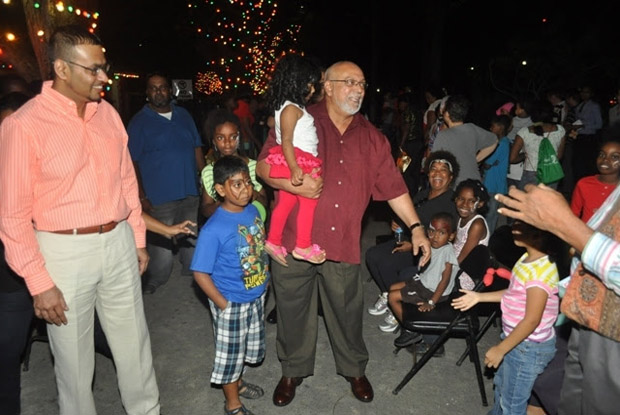 President Donald Ramotar and Minister Robert Persaud engage some of the children present at the tree light-up in the National Park